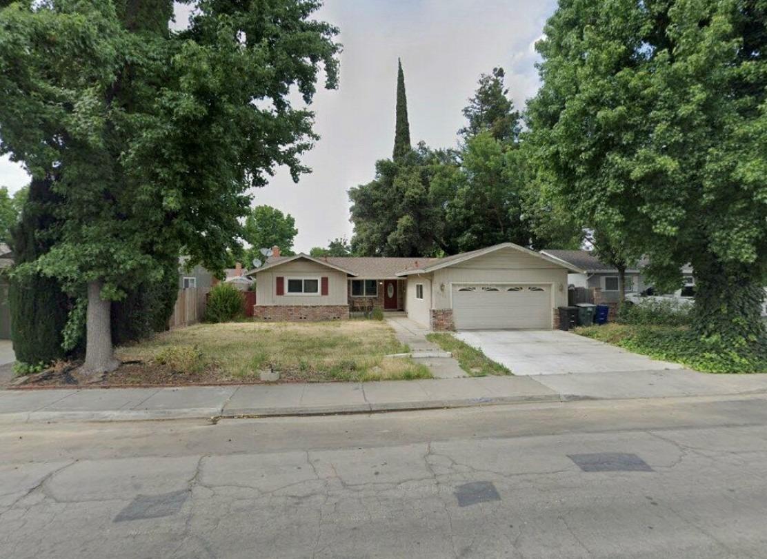 a front view of a house with a yard and trees