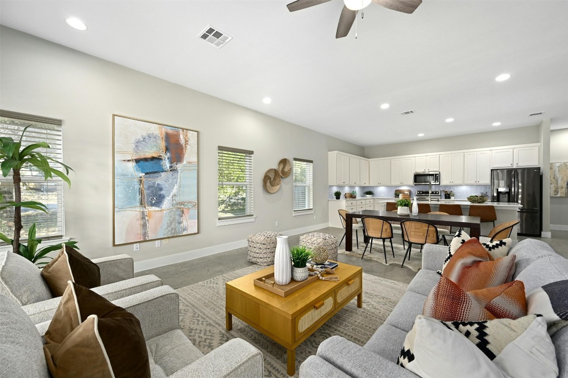 a living room with furniture kitchen view and a large window