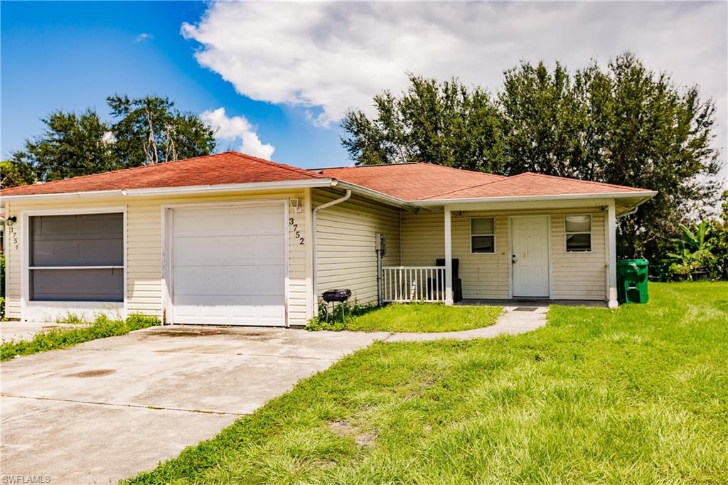 Single story home with a garage, a porch, and a front lawn