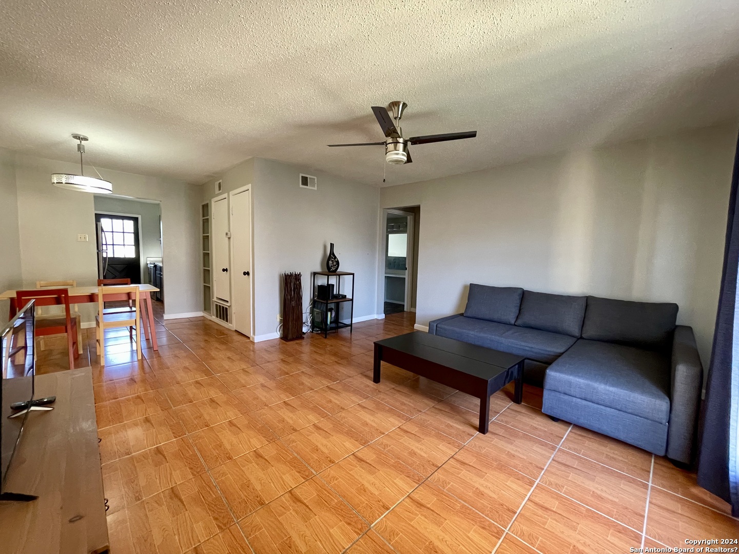 a living room with furniture and a dining table with wooden floor