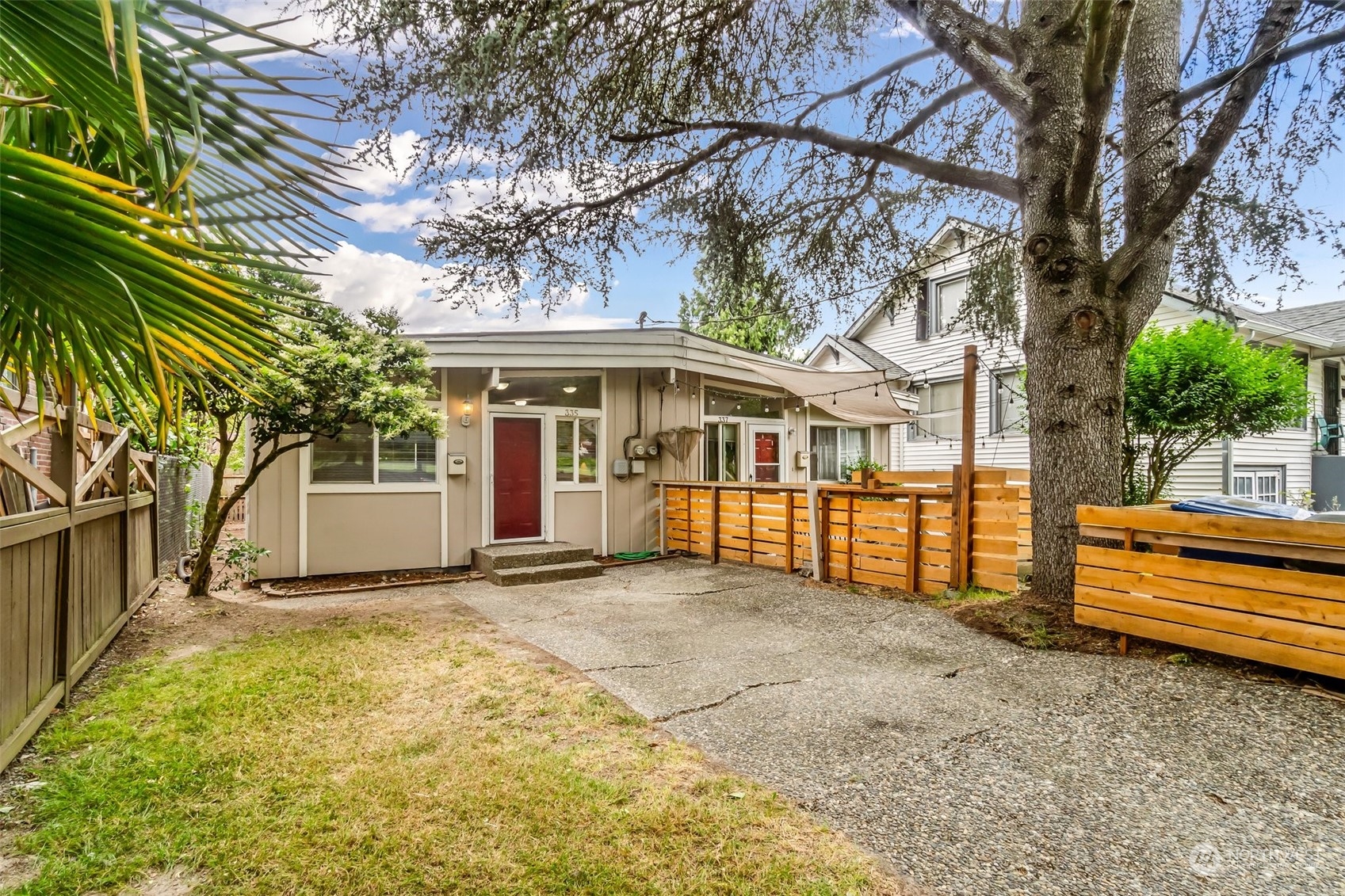 a view of a house with a large tree and a yard