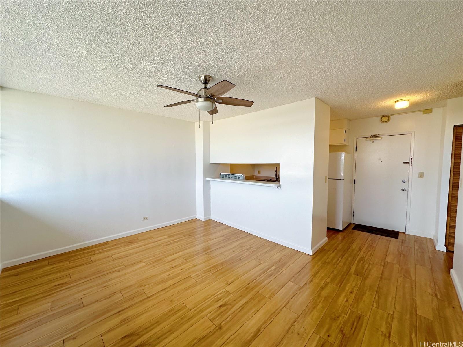 a view of a big room with wooden floor and a kitchen space