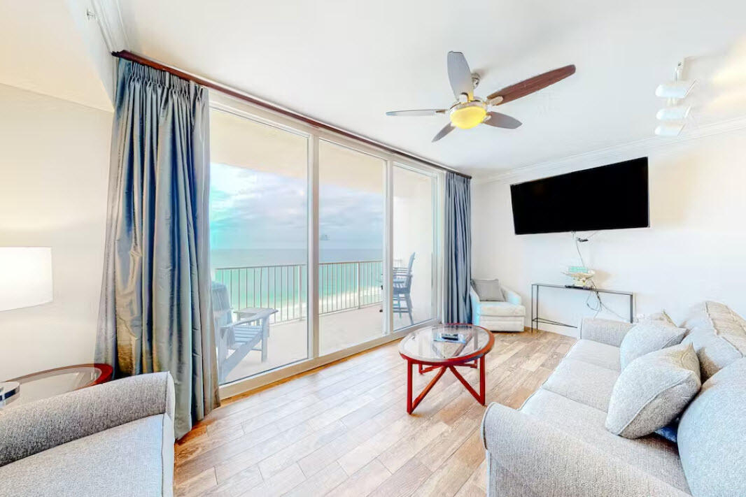 a living room with furniture a flat screen tv and a floor to ceiling window