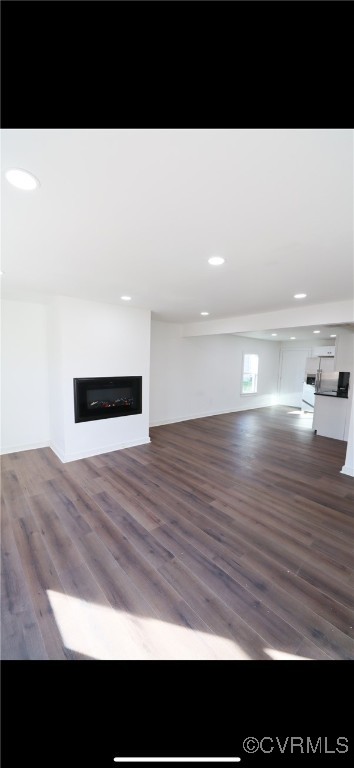 Unfurnished living room featuring dark hardwood /