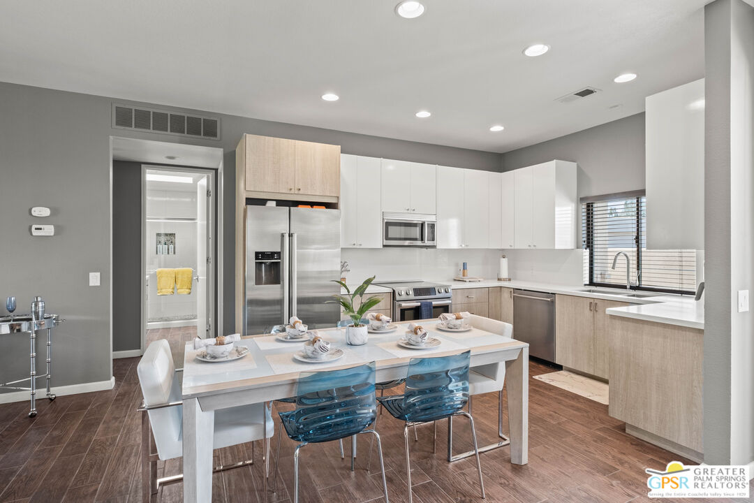 a kitchen with a dining table chairs cabinets and stainless steel appliances