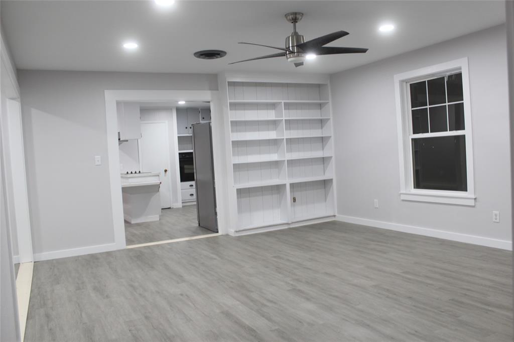 a view of an empty room with a window and wooden floor