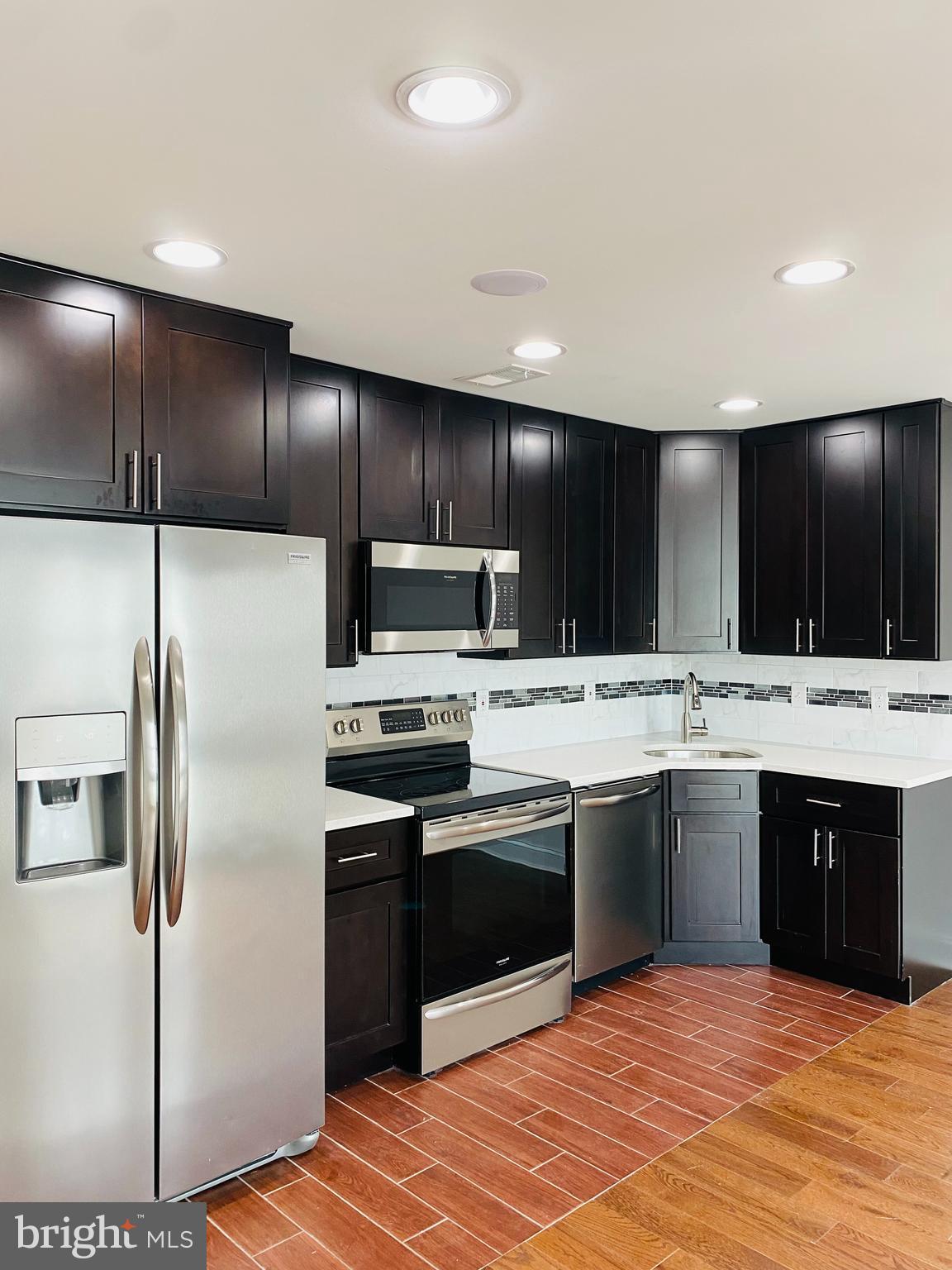 a kitchen with stainless steel appliances kitchen island granite countertop a sink and a refrigerator