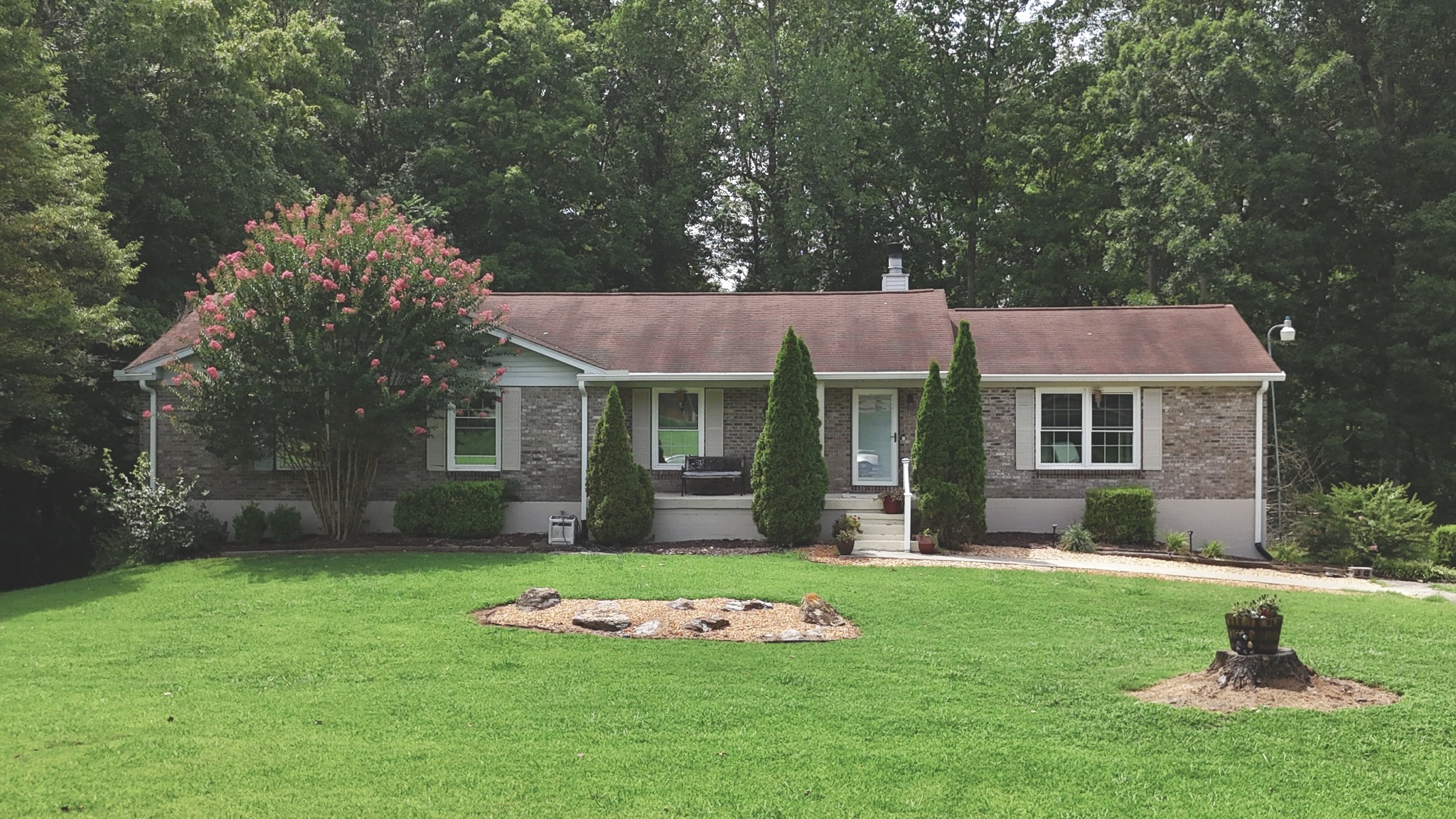 a front view of a house with a garden and trees