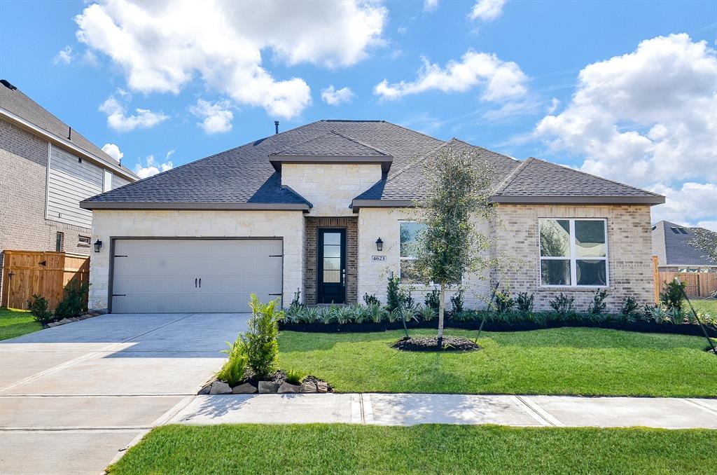 This is a charming single-story home with a modern brick exterior, featuring a two-car garage and a well-maintained front yard. The driveway and walkway are spacious, and the house is accented with tasteful landscaping.