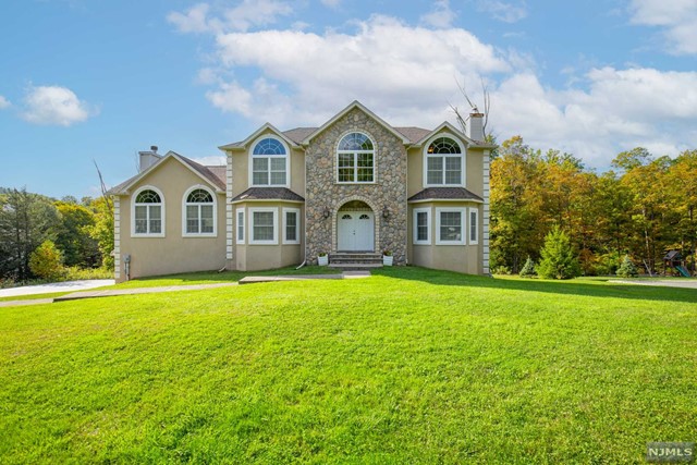 a front view of a house with garden and trees