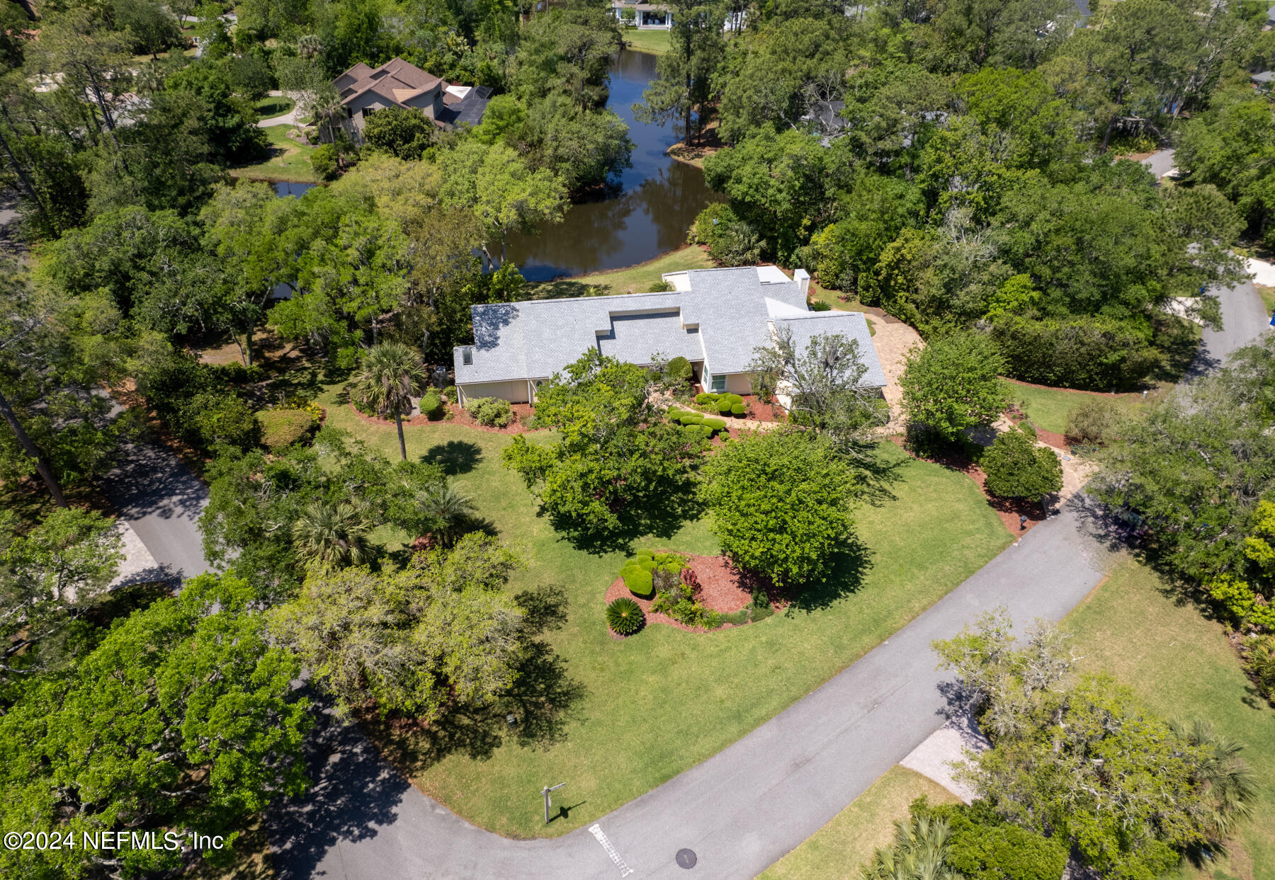 an aerial view of residential house with outdoor space and trees all around