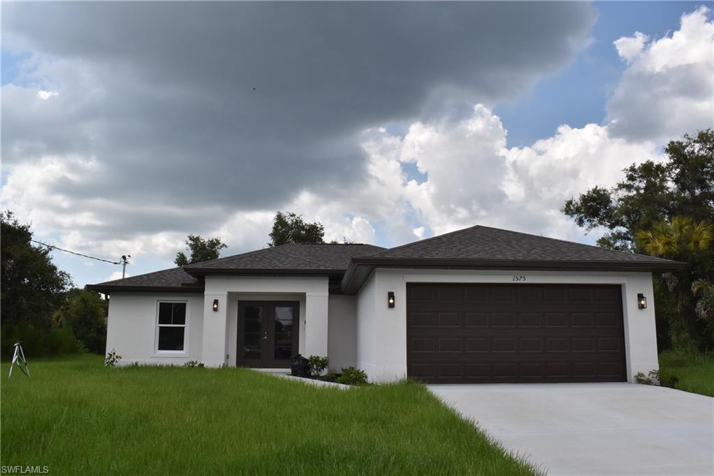 View of front of property featuring a front lawn and a garage