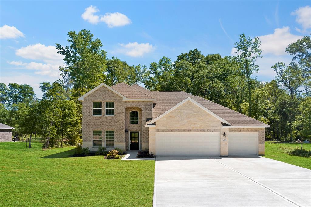 a front view of house with yard and trees in the background