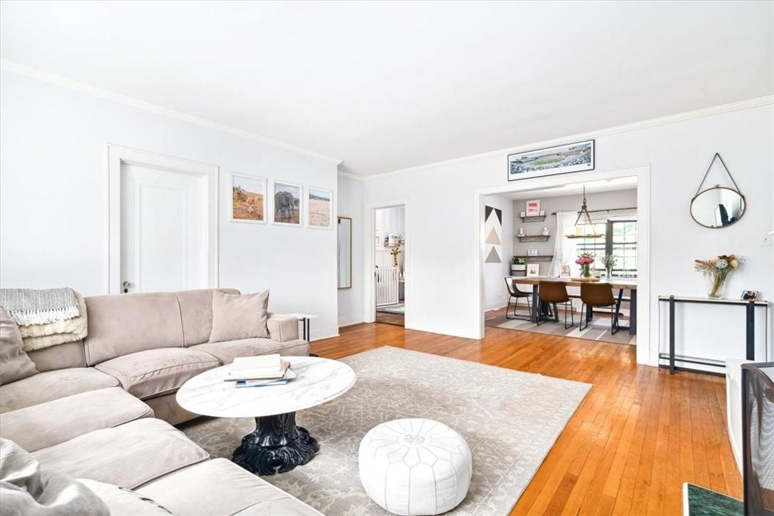 Living room with light hardwood / wood-style floors, ornamental molding, and a baseboard radiator