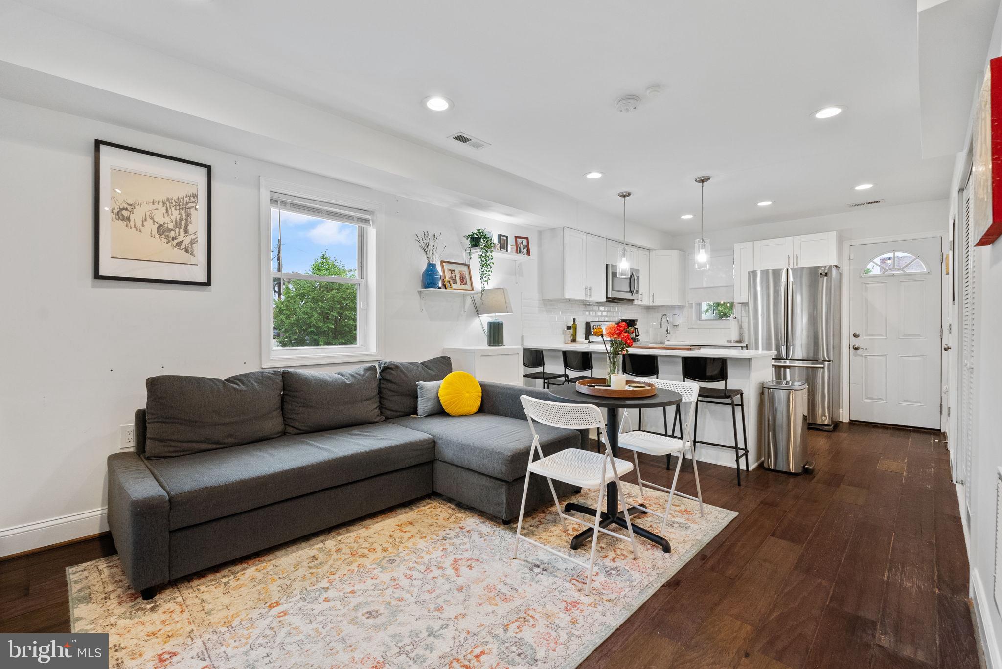 a living room with furniture and a dining table with wooden floor