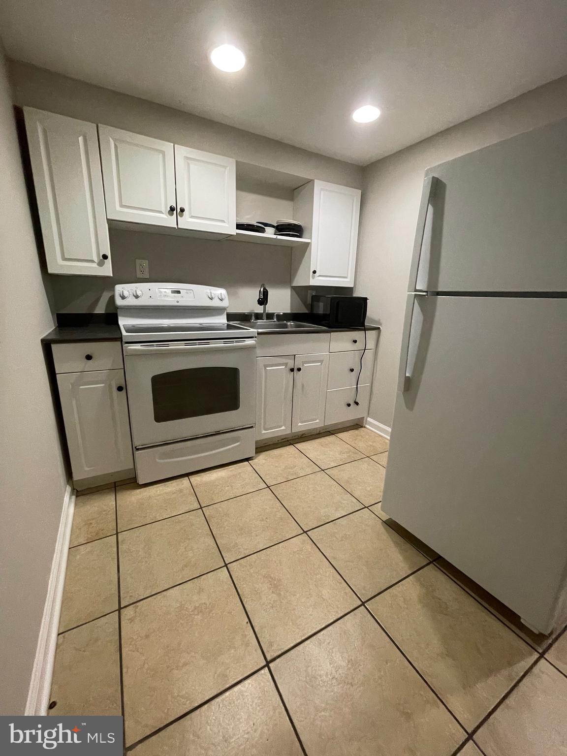 a kitchen with granite countertop a refrigerator sink and cabinets