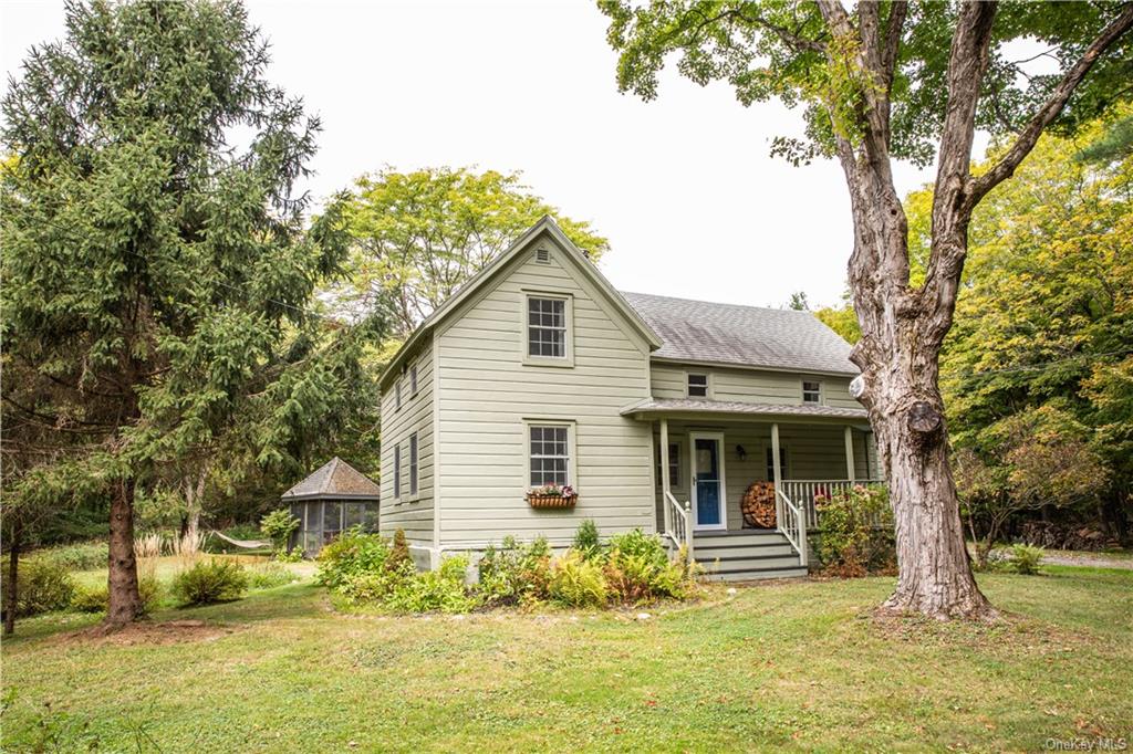 a front view of a house with a garden and tree