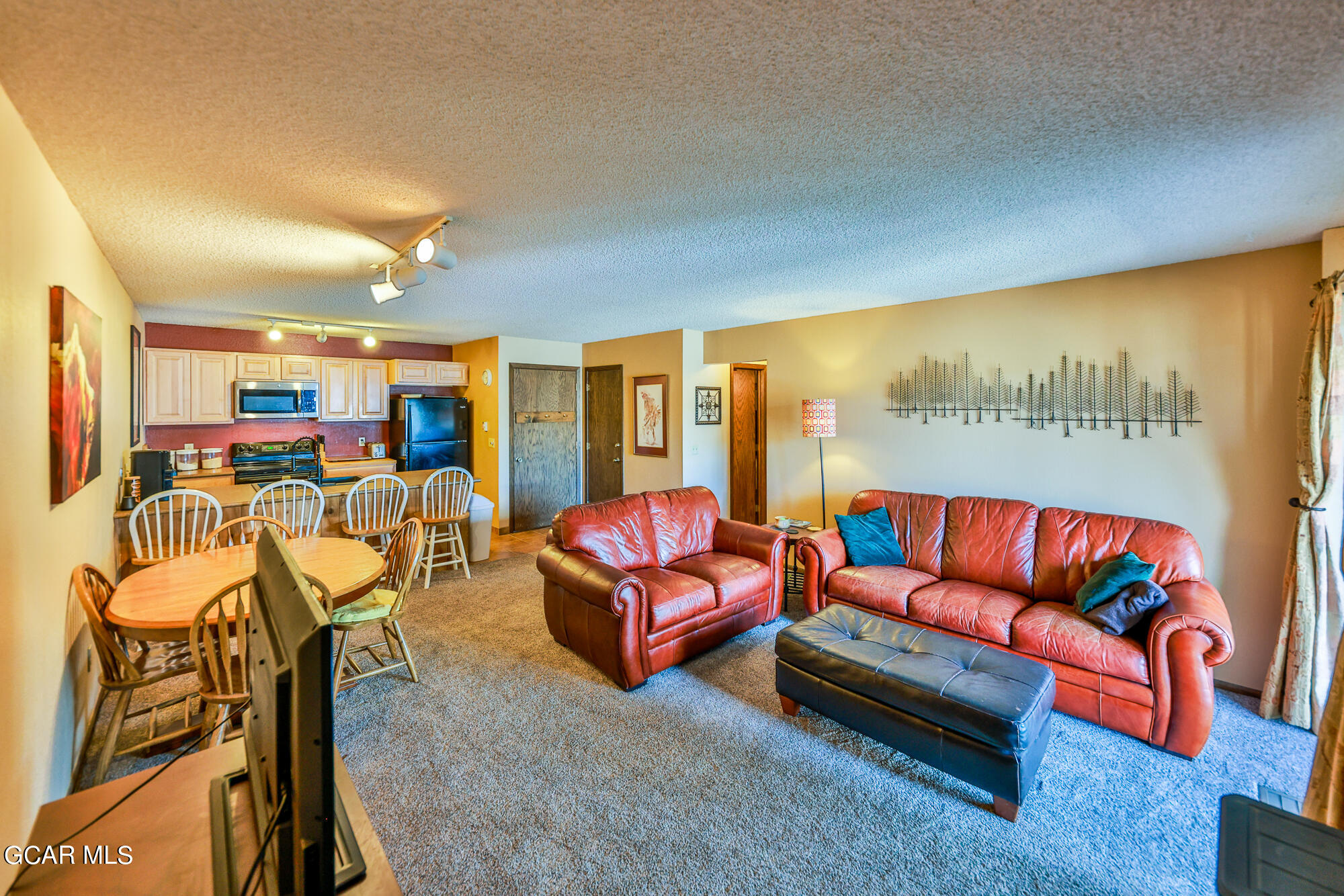 a living room with furniture kitchen view and a large window