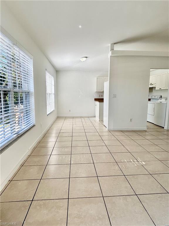 Unfurnished living room with washing machine and dryer and light tile patterned floors