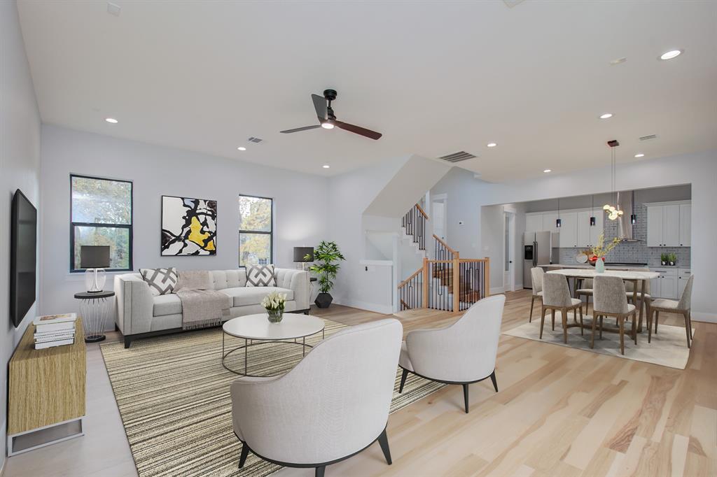 a living room with furniture kitchen view and a wooden floor