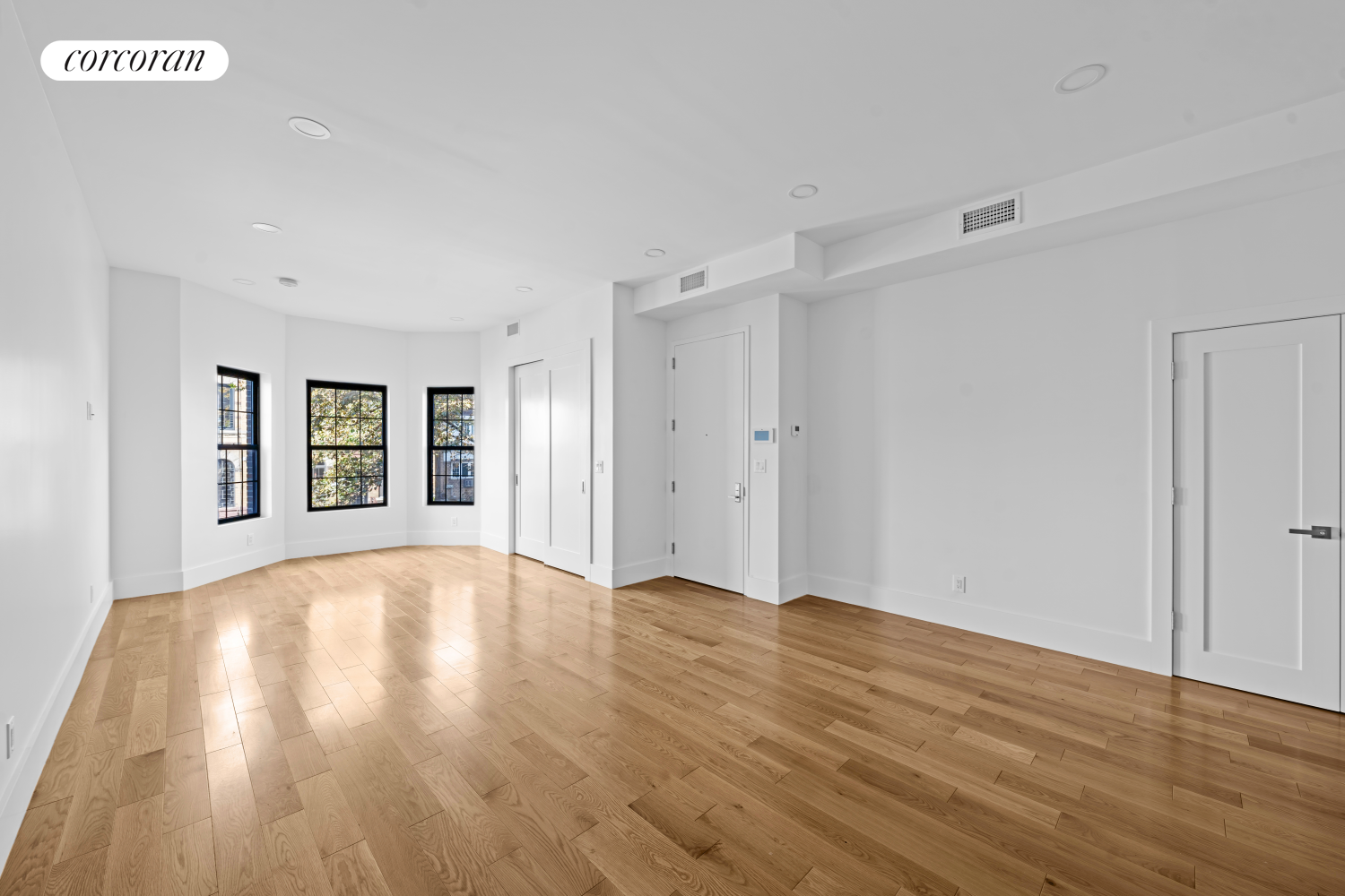 a view of an empty room with window and wooden floor