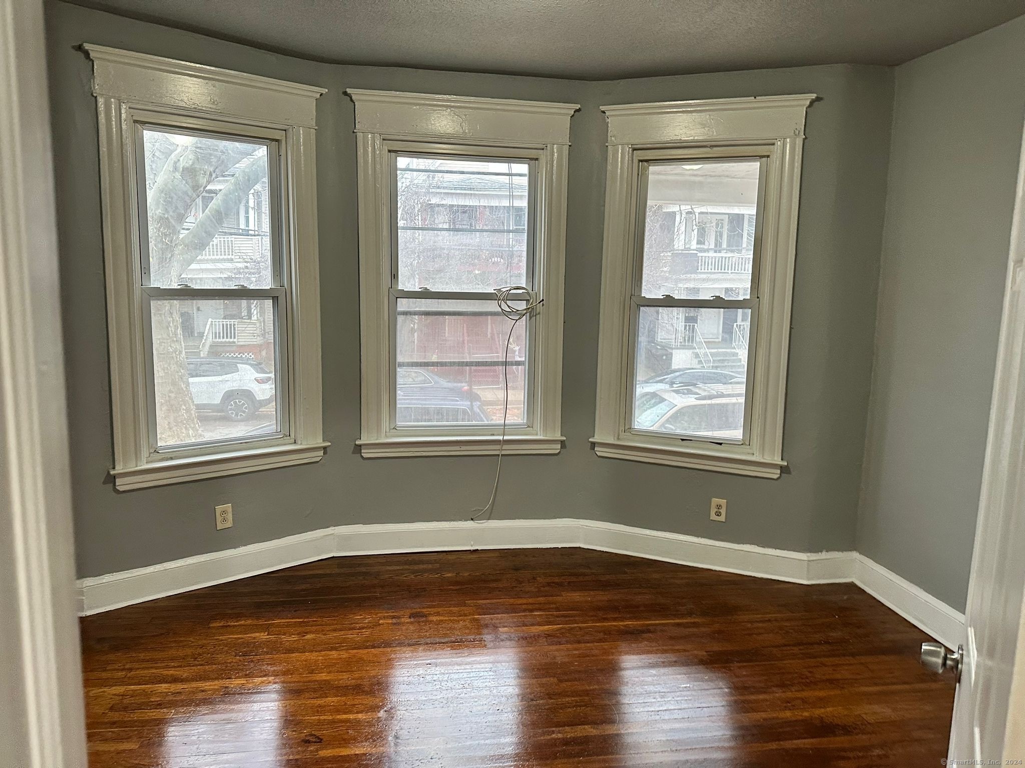 a view of empty room with wooden floor and fan