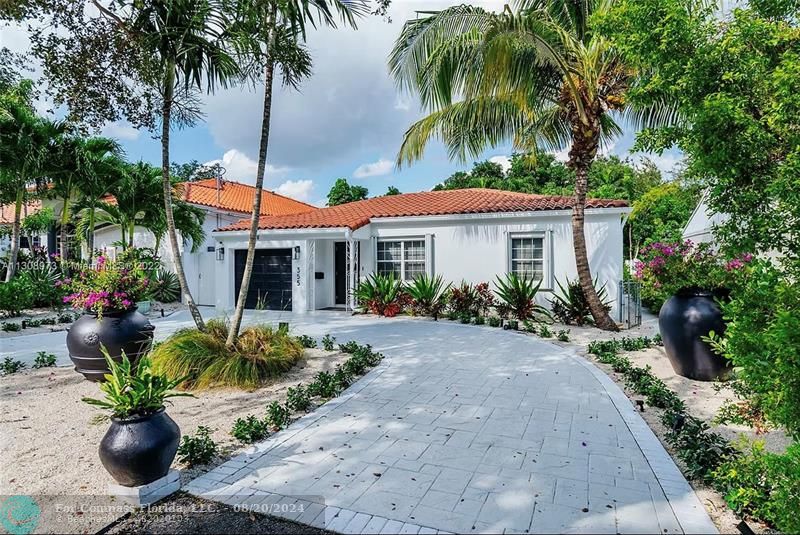 a front view of a house with a yard and potted plants