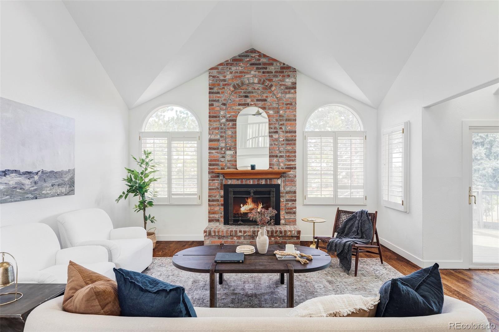 a living room with furniture a fireplace and large windows