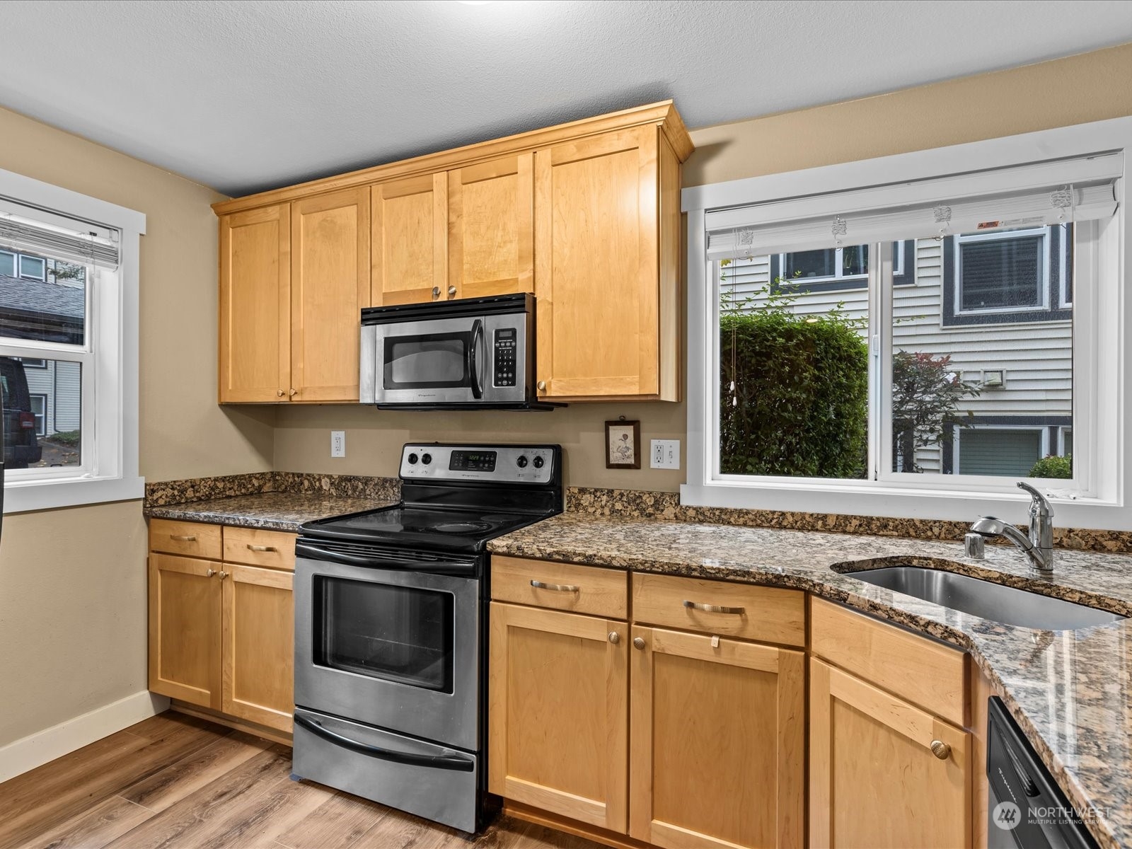 a kitchen with granite countertop a stove top oven cabinetry a sink and a granite counter top