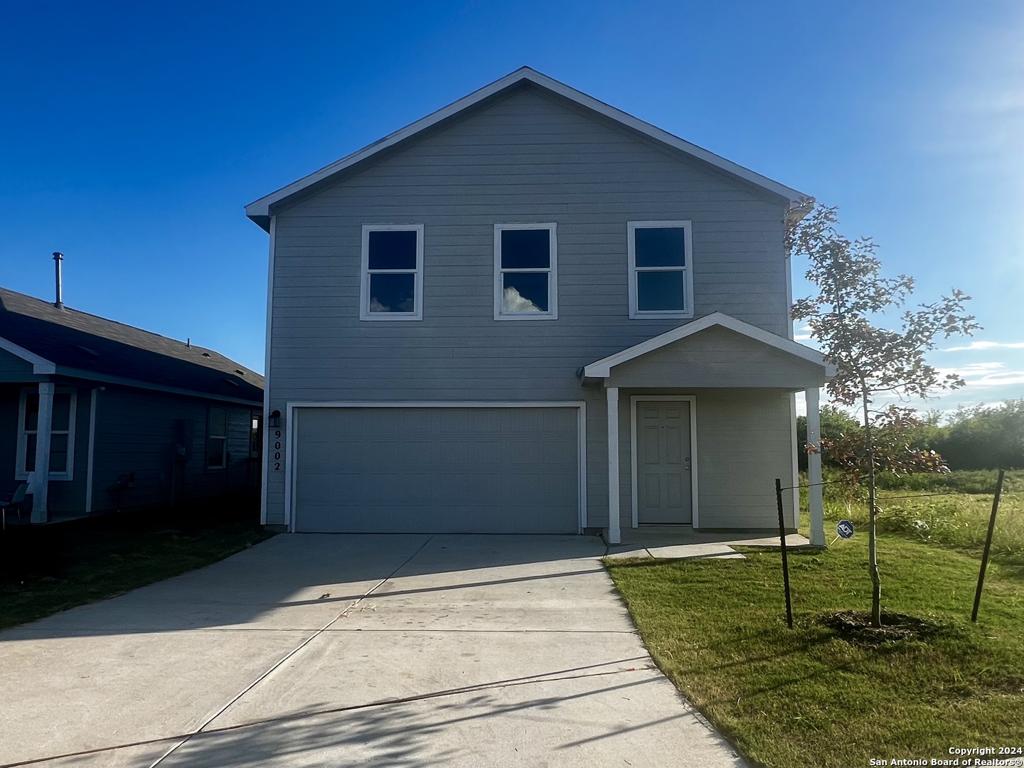 a view of backyard of house with wooden fence