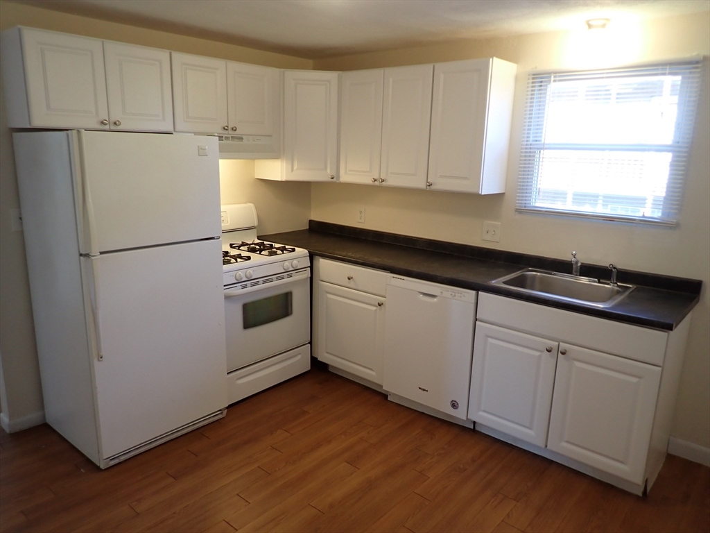 a kitchen with granite countertop white cabinets and white appliances