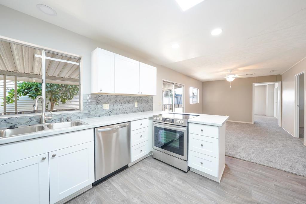 a kitchen with granite countertop white cabinets and white stainless steel appliances