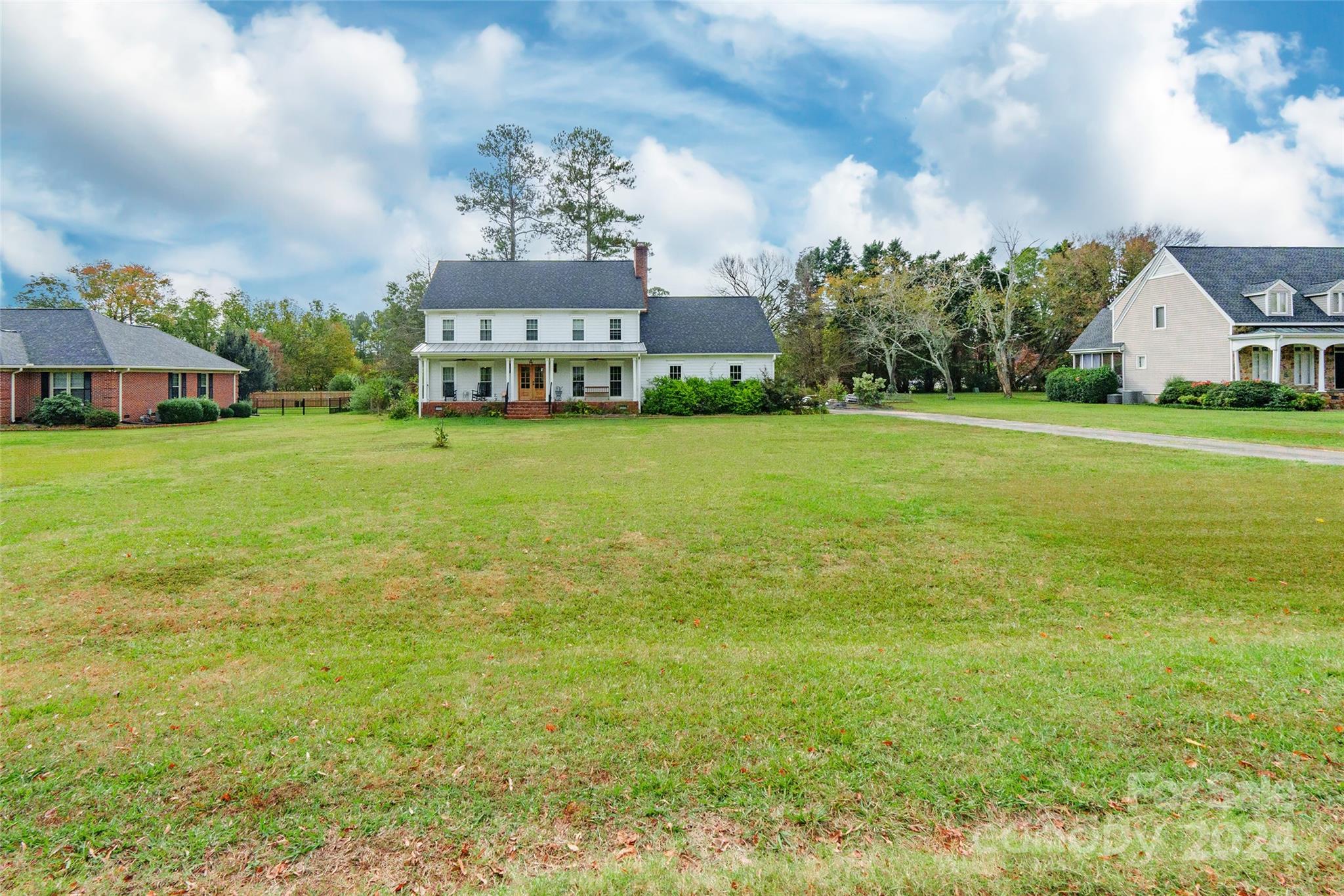 a view of a big house with a big yard and large trees