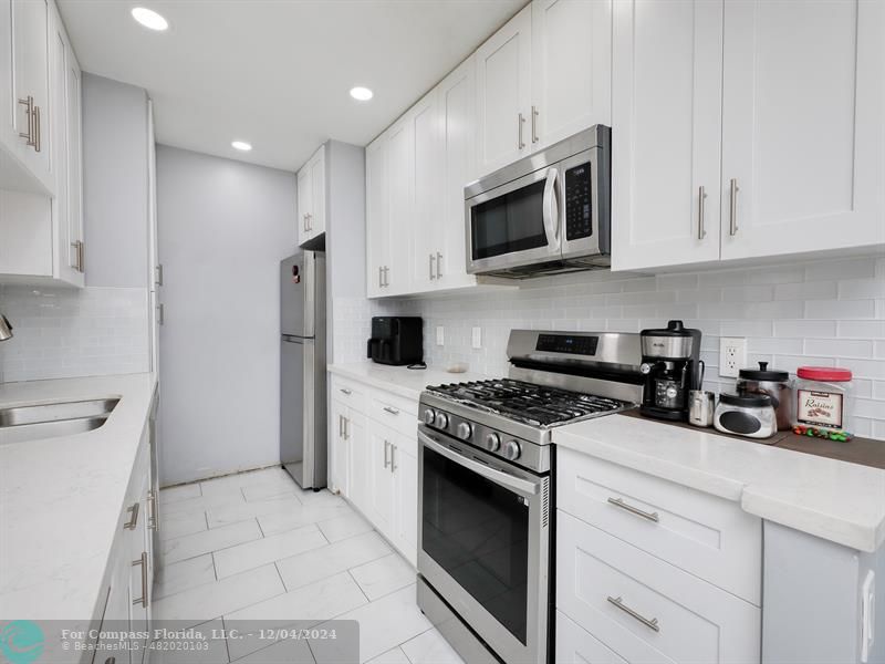 a kitchen with stainless steel appliances white cabinets and a stove a oven with white countertops