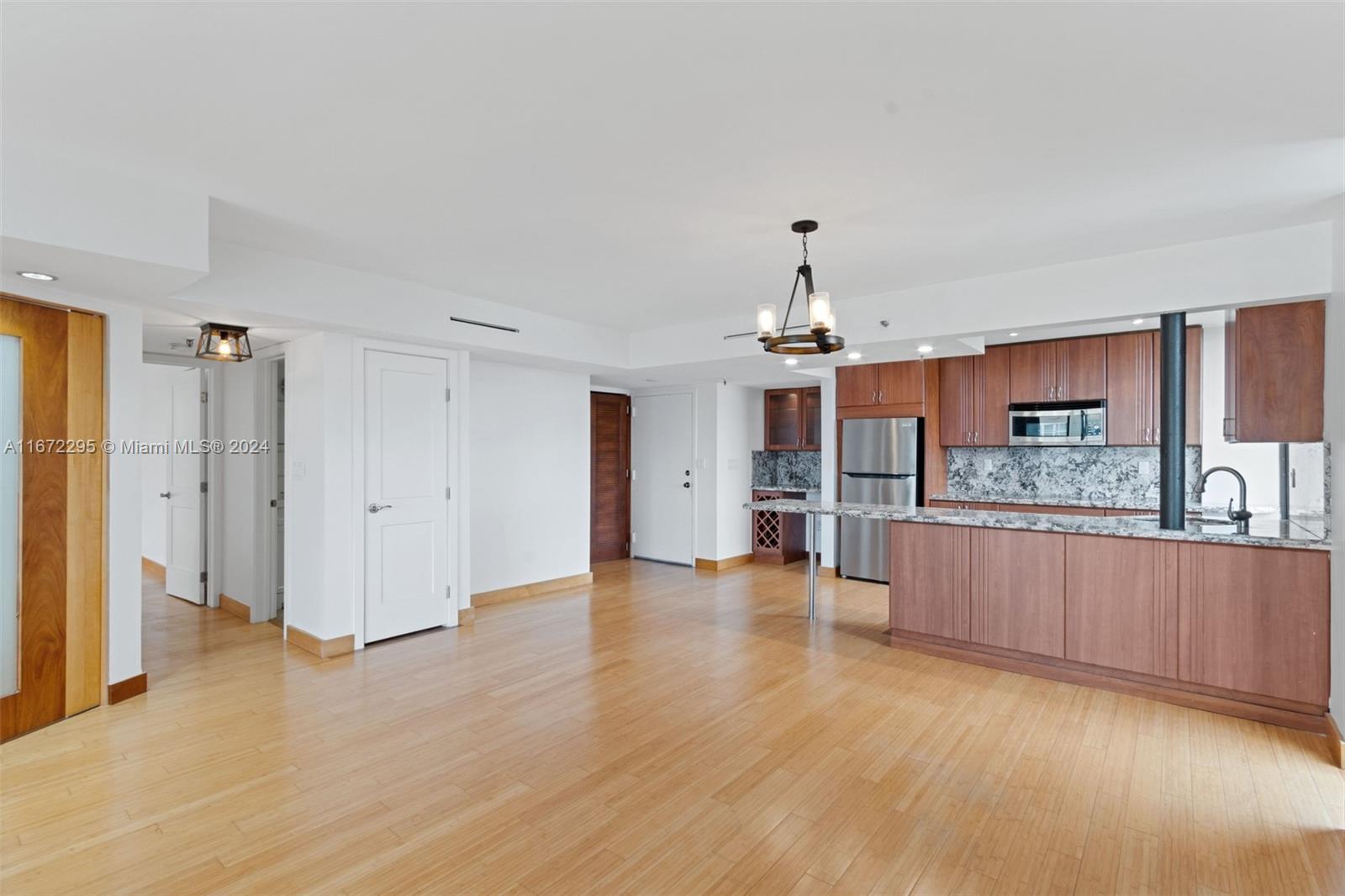 a view of a kitchen with granite countertop wooden floor and stainless steel appliances