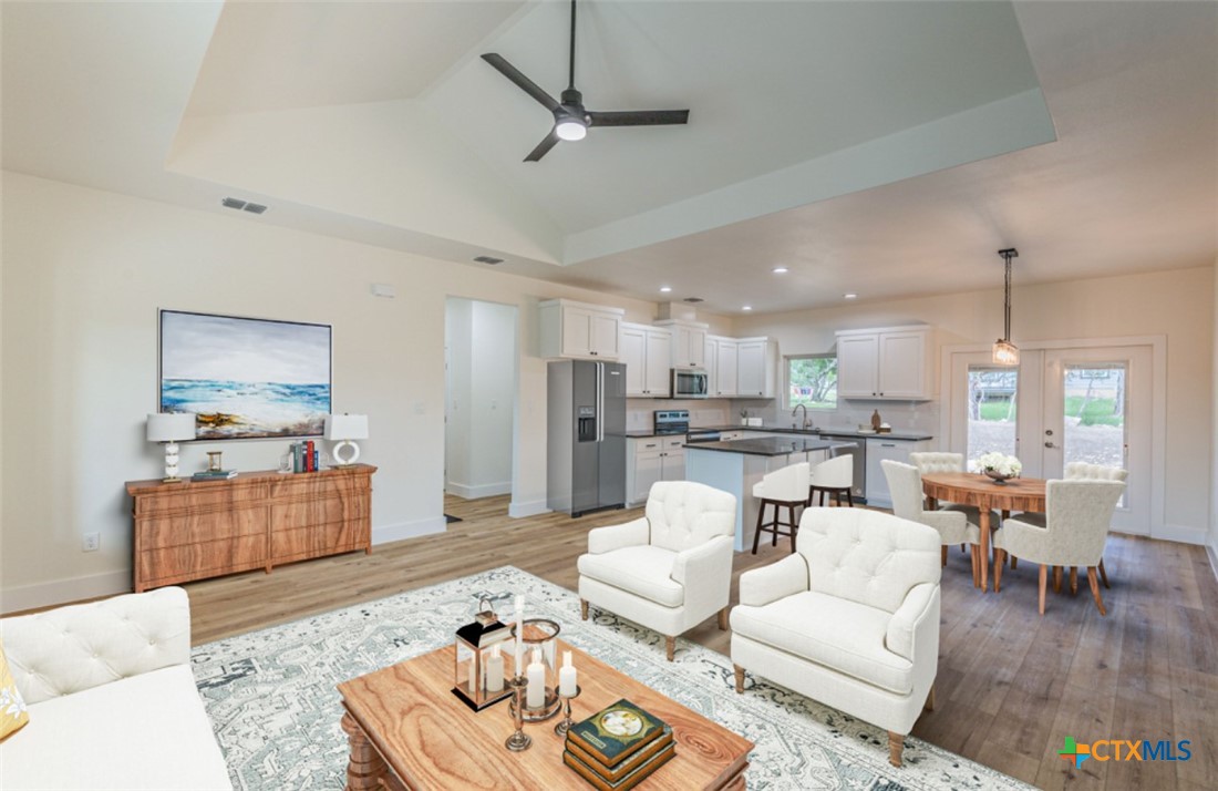 a living room with furniture kitchen view and a wooden floor