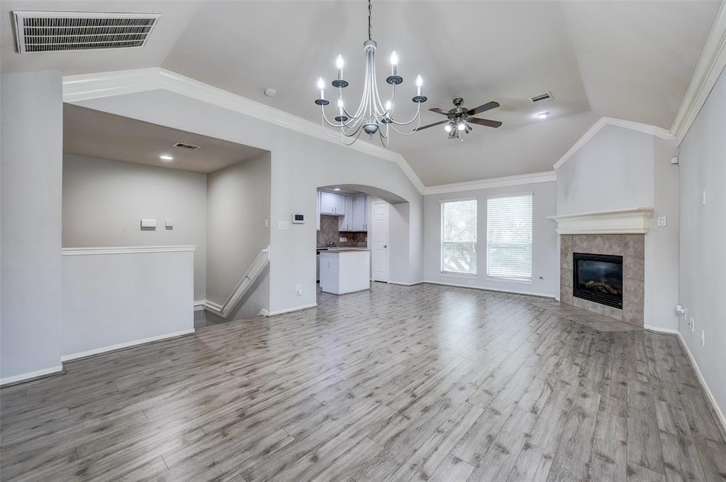 an empty room with wooden floor fireplace and windows