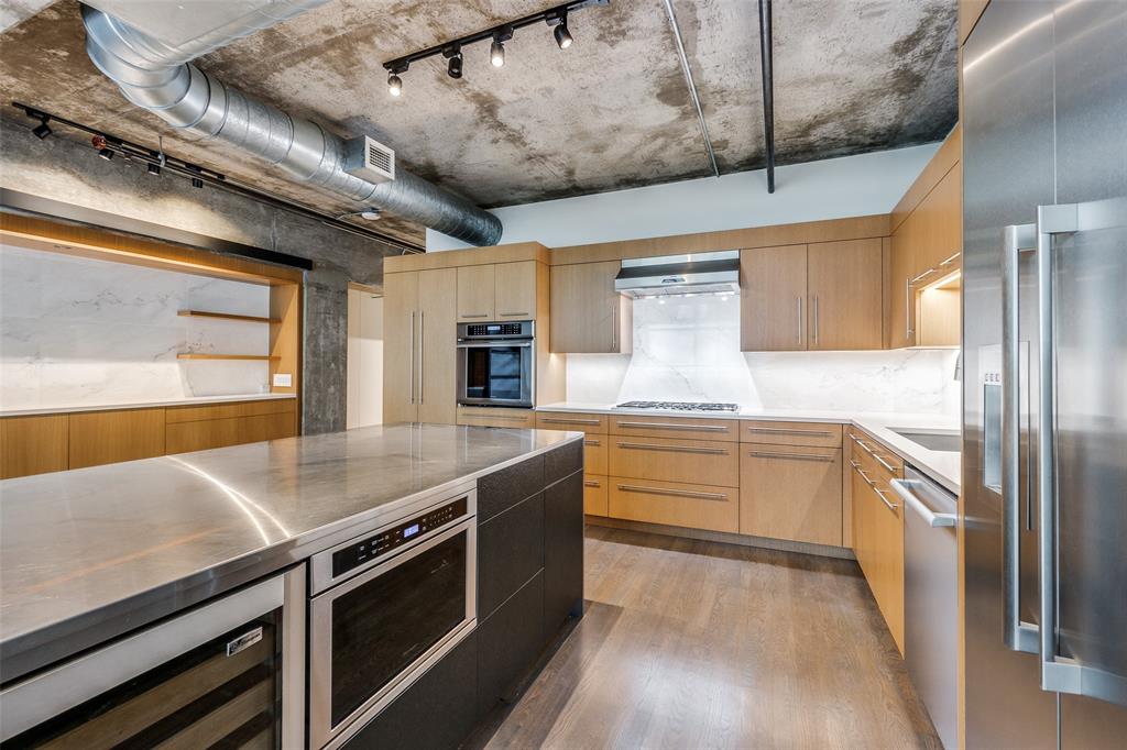 a kitchen with stainless steel appliances granite countertop a sink a stove and a wooden floors