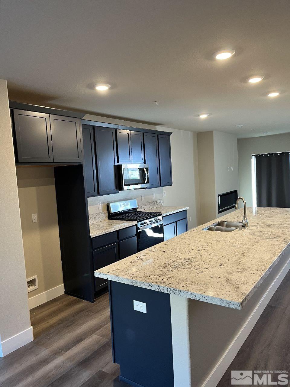 a kitchen with granite countertop a refrigerator a sink and wooden cabinets