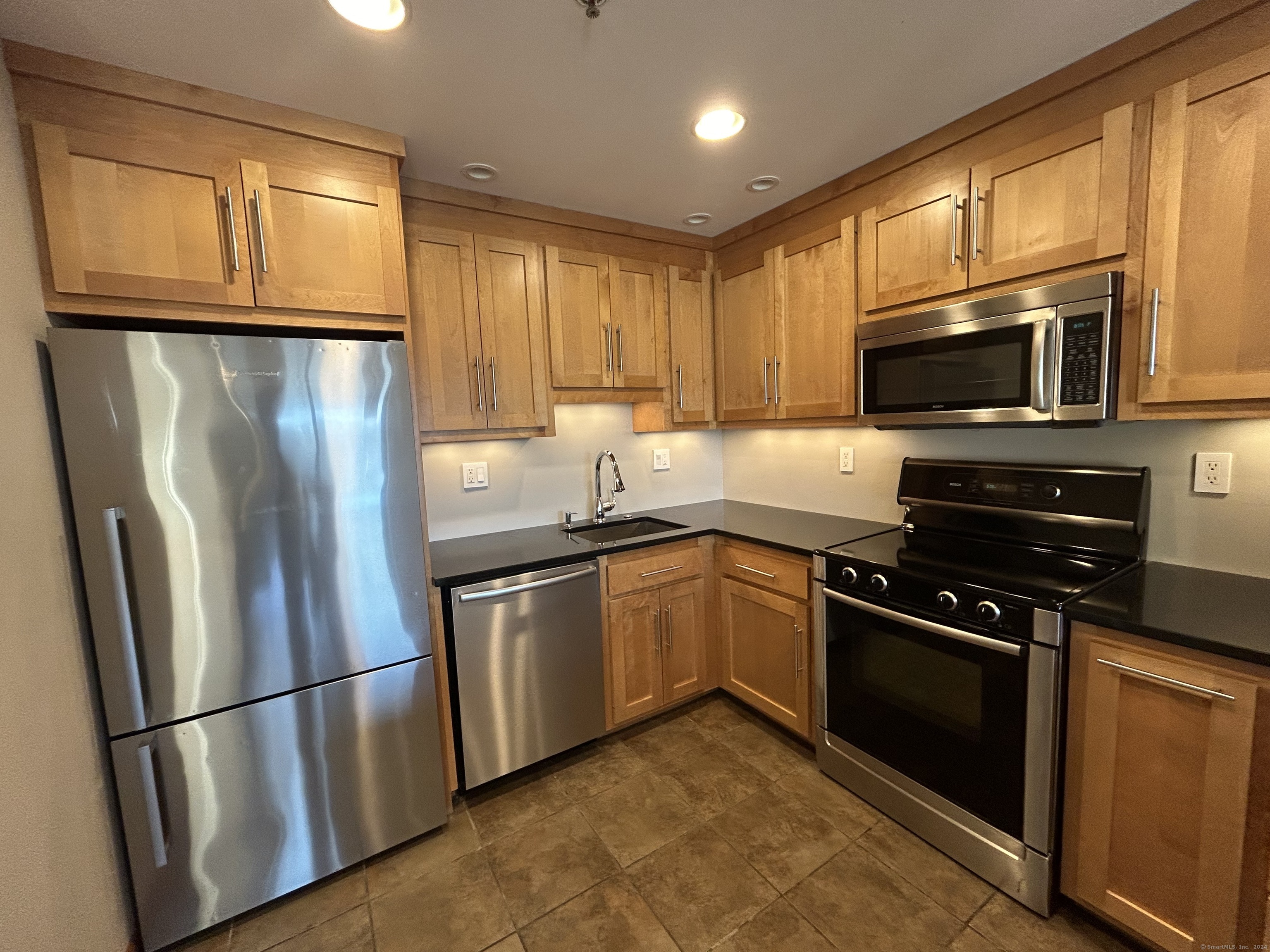 a kitchen with stainless steel appliances granite countertop a refrigerator stove top oven a sink and dishwasher