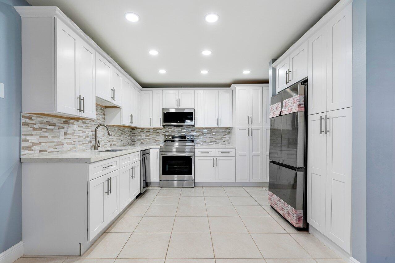 a kitchen with granite countertop a refrigerator oven a sink and cabinets