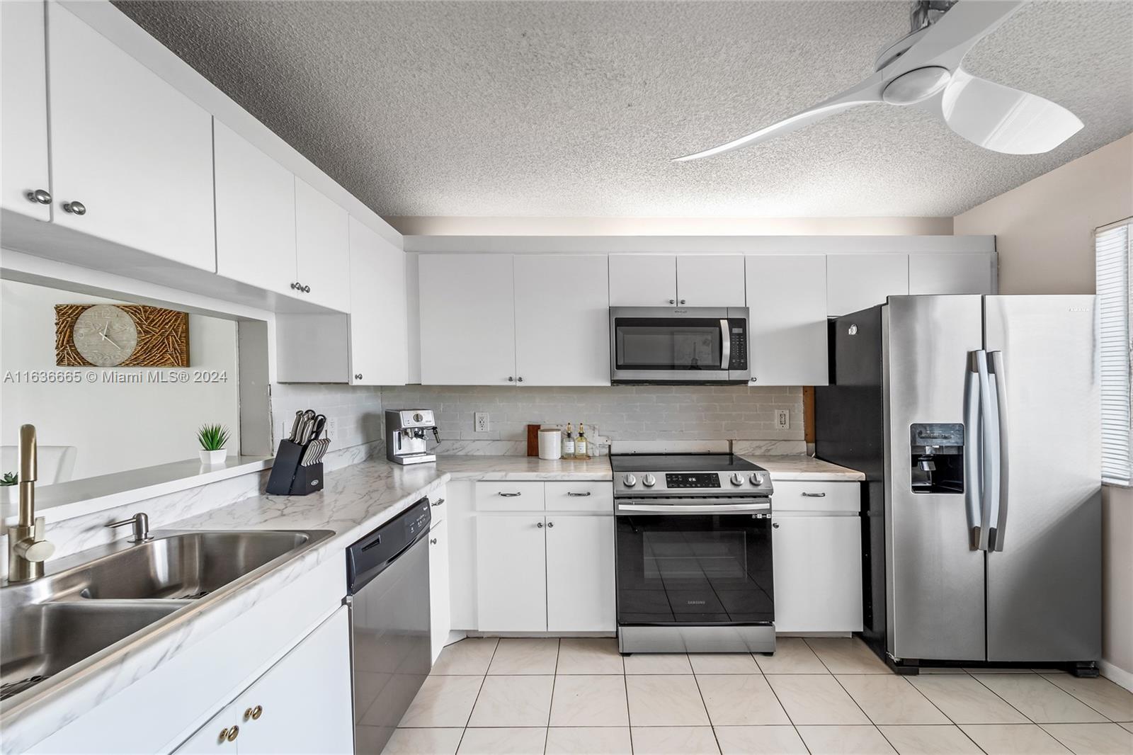 a kitchen with granite countertop white cabinets stainless steel appliances and a sink