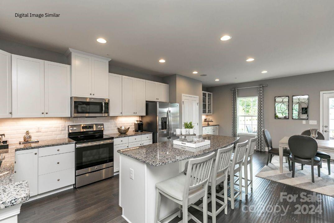 a view of kitchen with granite countertop microwave stove top oven and cabinets