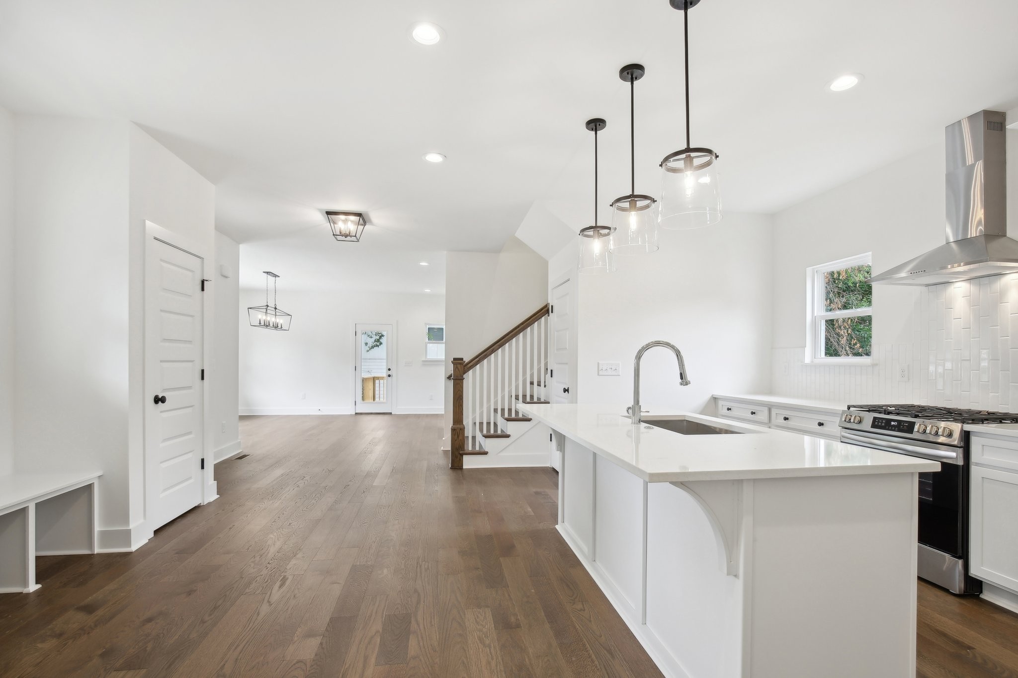 a kitchen with stainless steel appliances granite countertop a sink a stove and a wooden floor