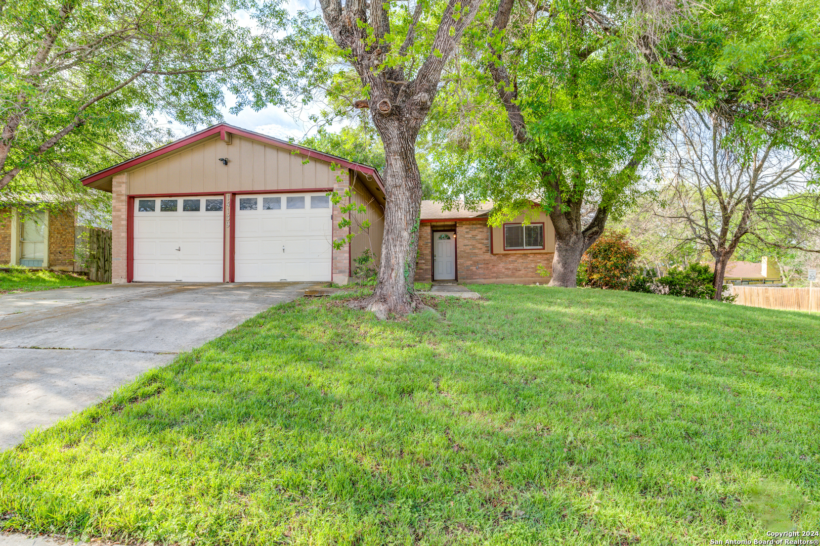 a front view of a house with yard and tree