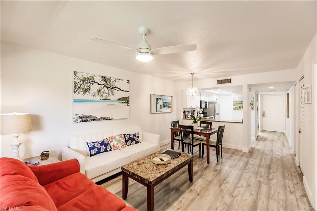 Living room featuring ceiling fan with notable chandelier and light wood-type flooring