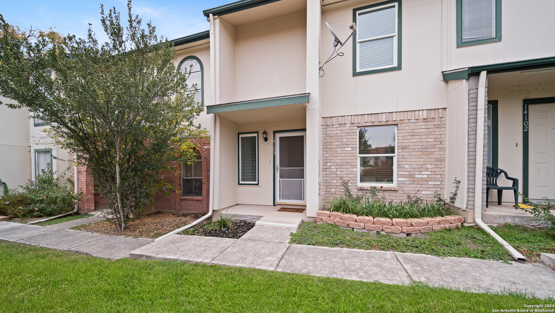 a view of a house with brick walls and a yard with plants