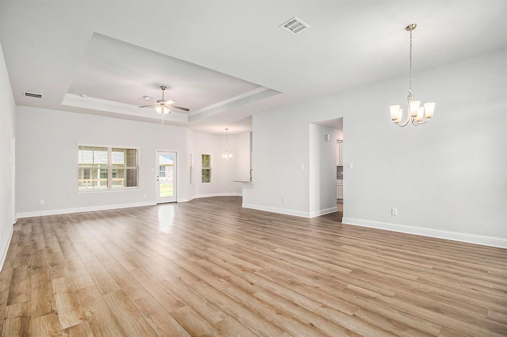 an empty room with wooden floor chandelier and windows