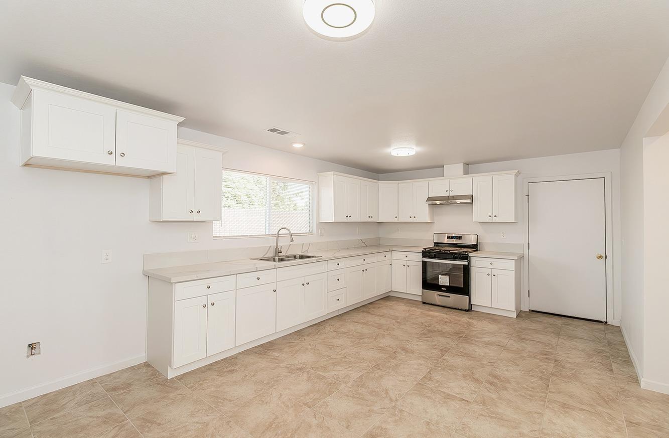 a kitchen with granite countertop a sink stove and refrigerator