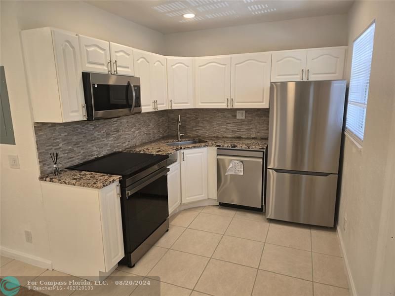 a kitchen with stainless steel appliances granite countertop a stove a refrigerator and a microwave